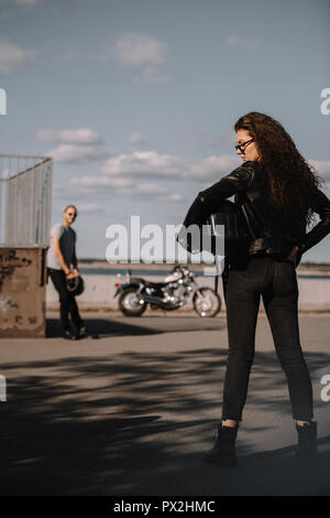 Ragazza con casco e in piedi nella parte anteriore del fidanzato con moto Foto Stock