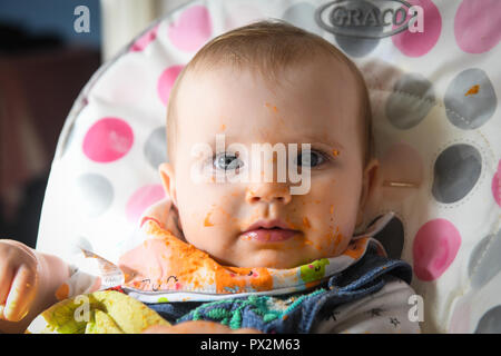 Un bambino di colore bianco con gli occhi blu nella foto con il cibo oltre che della faccia come si inizia a led bambino allo svezzamento. Foto Stock