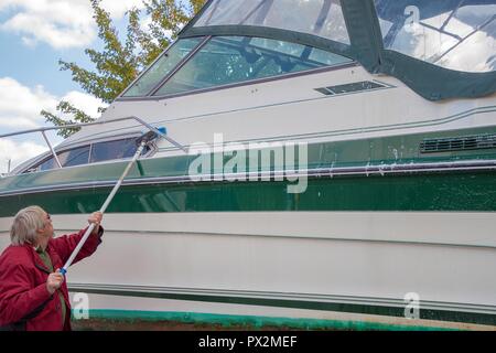 Uomo caucasico potenza di lavaggio barca con manico lungo pennello Foto Stock