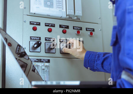 Gli ingegneri di sesso maschile sono il controllo dell'impianto elettrico mediante il programma nel computer portatile. Foto Stock