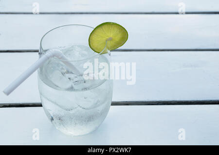 Soda Water ha bolle galleggianti in acqua, ​​lime a fette tagliate a fette ​​in vetro, collocato su un tavolo bianco, è un ristorante. A Bangkok, in Thailandia. Foto Stock