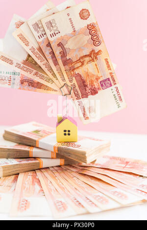 Modello di casa impostata sulla banconota per il concetto di investimenti del fondo di ipoteca e finanza mutuo casa.Piccola casa in legno sullo sfondo delle banconote in russo. Immagine simbolica di acquisto o di affitto di una casa. Foto Stock