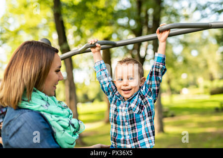 Un adorabile ragazzino godendo il suo tempo in una struttura di gioco con la madre Foto Stock