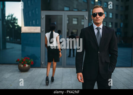 Bodyguard gravi in tuta e occhiali da sole, custodendo Foto Stock