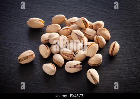 Pistacchi salati su un nero ardesia sfondo. Close up. Foto Stock