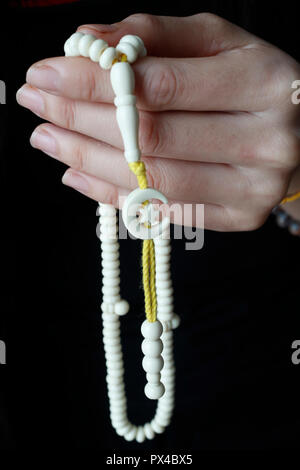 Donna musulmana pregando con grani di preghiera. Close-up sulle mani. Foto Stock