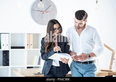 I colleghi sono la revisione di un progetto su carta. Comunicare le liste di controllo, attività, scadenze, business, i documenti, i responsabili dei progetti Foto Stock