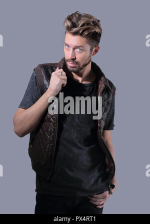 Perplesso giovane uomo accarezzare un toccante barba, guardando la telecamera su uno sfondo grigio Foto Stock