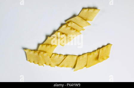Asciugare la pasta italiana chiamato pantacce su uno sfondo bianco ,rhombus -pasta sagomata con bordo ondulato ,divertente composizione , studio shot , vista superiore Foto Stock
