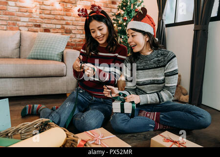 Ragazza giovane con i cervi mediante taglio a forbice il verde bow. adorabile signore lavorano insieme a casa incarto di regali per amici. il Natale sta arrivando e att Foto Stock