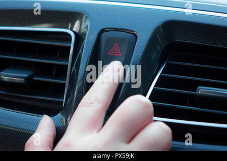 La donna spinge un pulsante in auto Foto Stock