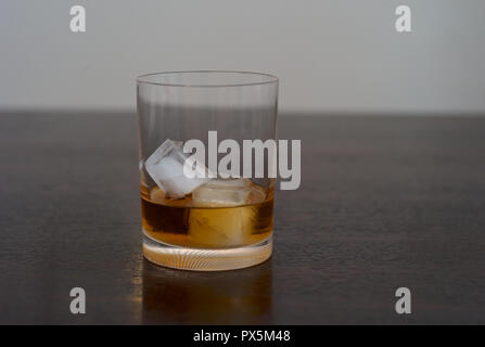 Whiskey Bourbon, Scotch o Rum sulle rocce in un elegante bicchiere al buio su un tavolo di legno Foto Stock