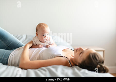 Ritratto di una madre bella con il suo bimbo di due mesi in camera da letto Foto Stock