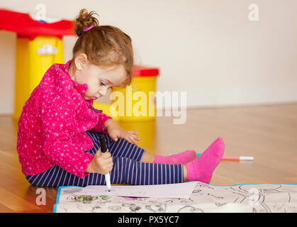 Due-anno-vecchia ragazza richiama e colori sul pavimento a casa. Foto Stock