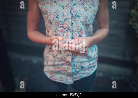 Un nervoso giovane donna è raccolta la sua chiodi nel giardino Foto Stock