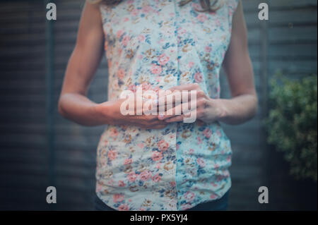 Un nervoso giovane donna è raccolta la sua chiodi nel giardino Foto Stock