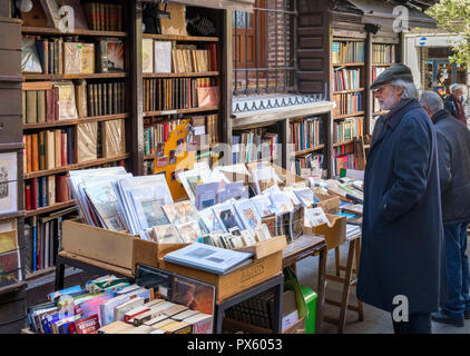 L'uomo la navigazione libri su una bancarella vendendo seconda mano libri e stampe d'arte, Calle del Arenal, Madrid, Spagna Foto Stock