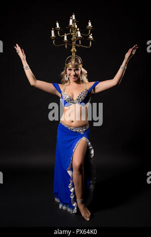 Bellissima danzatrice del ventre di eseguire la danza del ventre con candela titolare su sfondo nero. Foto Stock