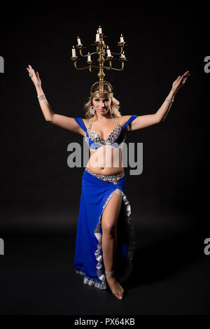 Bellissima danzatrice del ventre di eseguire la danza del ventre con candela titolare su sfondo nero. Foto Stock