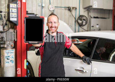 Un ritratto di bello meccanico sulla base di auto nel negozio di riparazioni auto Foto Stock