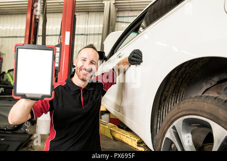 Un ritratto di bello meccanico sulla base di auto nel negozio di riparazioni auto Foto Stock