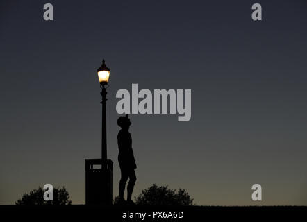 Una silhouette di un pareggiatore prendendo un respiro dopo aver eseguito alla sommità di Primrose Hill, Londra. Foto Stock