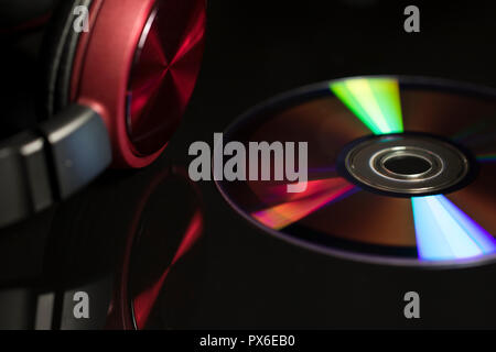 Il concetto di musica con close up di un CD e le cuffie. Una tecnologia ormai superata. La tecnologia dei compact disc per la personale di ascolto musicale. Foto Stock