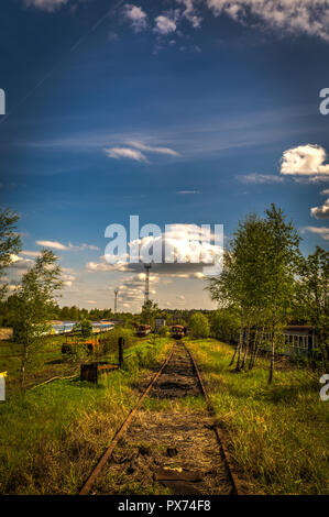 Vecchie locomotive in treno cimitero in estate con erba verde e alberi in background e grande cielo molto nuvoloso Foto Stock