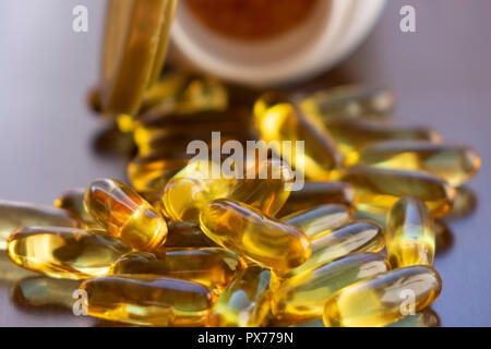 Olio di pesce di capsule con omega 3 e vitamina D in una bottiglia di vetro sulla texture in legno, dieta salutare concetto,close up shot. Foto Stock
