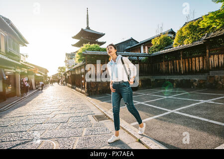 Lunghezza completa foto di una femmina permanente di viaggiatori su strada con pagoda in background. Turista a piedi nella città giapponese sul Giappone viaggi. asi Foto Stock