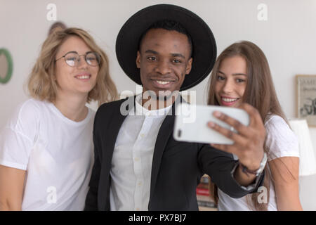 Gruppo multirazziale di amici fare un selfie. Due giovani donne e uomini che indossano un abbigliamento informale. Foto Stock