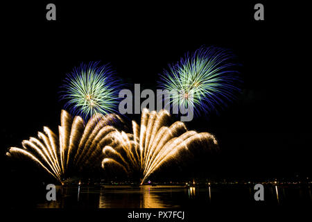 Giganti blu e arancione esplosioni di fuochi d'artificio riflettendo in acqua Foto Stock