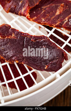 Prugne secche prugne snocciolate in ciotola a forma di cuore su sfondo nero Foto Stock