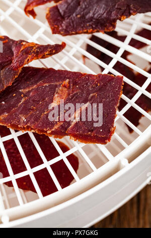Prugne secche prugne snocciolate in ciotola a forma di cuore su sfondo nero Foto Stock