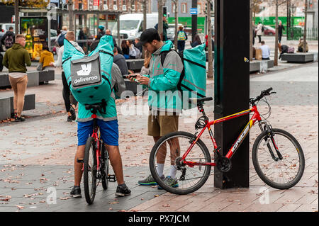 I piloti Deliveroo attendere di ricevere i loro ordini su Grand Parade, Cork, Irlanda. Foto Stock