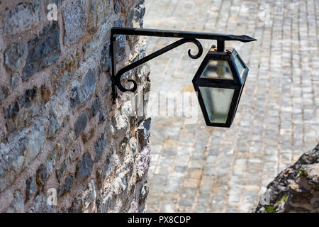 Close-up di immagini in stile vintage di ferro nero lampada di strada sulla muratura a secco muro di pietra, la città vecchia di Budva, Montenegro. Elevato angolo di visione Foto Stock