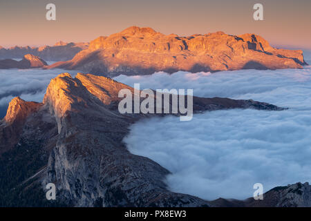 Alpenglow all'alba sul gruppo montuoso del Sella e sulle vette del Settsass. Marea di nuvole. Le Dolomiti. Alpi Italiane. Europa. Foto Stock
