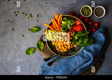 Ciotola di Buddha con ceci, baby spinaci e altre verdure organiche su calcestruzzo con uno sfondo con spazio di copia Foto Stock