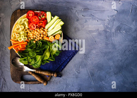 Ciotola di Buddha con ceci, baby spinaci e altre verdure organiche su calcestruzzo con uno sfondo con spazio di copia Foto Stock