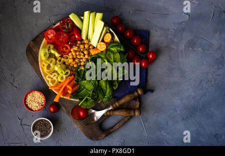 Ciotola di Buddha con ceci, baby spinaci e altre verdure organiche su calcestruzzo con uno sfondo con spazio di copia Foto Stock