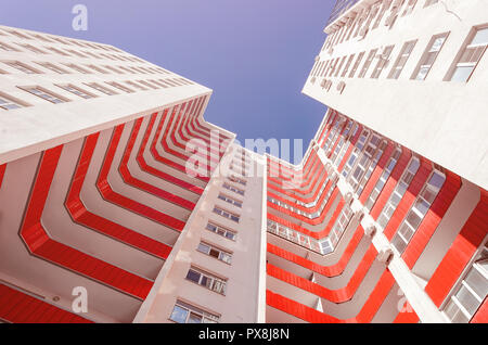 Vista di un edificio residenziale a partire dal basso verso l'alto. Casa bianca con balconi rosso in un giorno caldo e soleggiato Foto Stock
