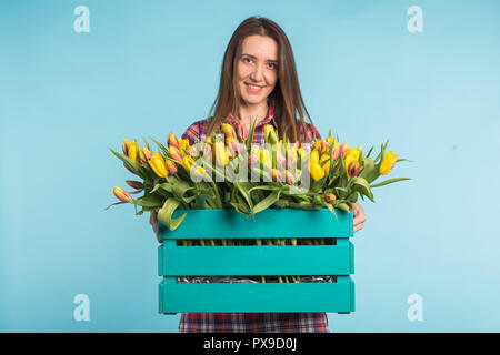 Donna felice ridere in studio con box di fiori sulle mani Foto Stock