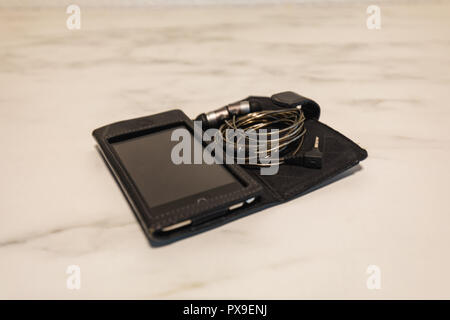 Smartphone con cuffie grigio su una lastra di marmo closeup Foto Stock