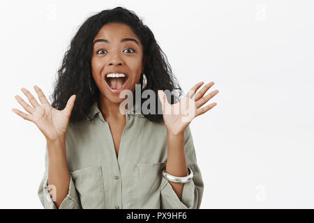 Vita-up shot di entusiasti affascinante di carnagione scura donna con ricci di acconciatura elegante sollevando le palme in emozione gesto sorridente largamente con aperto dalla bocca di divertimenti Foto Stock