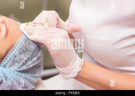 Persone e cosmetologia nozione - Stretta di mano di esperti estetista iniettare botox nelle femmine di fronte. Foto Stock