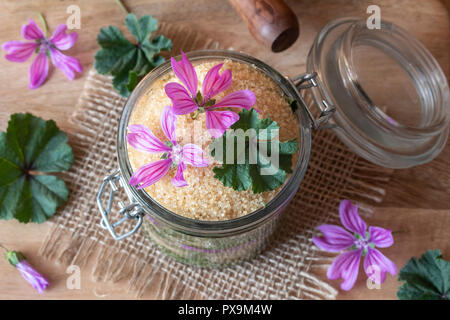 Preparazione di uno sciroppo a base di erbe contro la tosse da selvatici comuni fiori malva, di foglie e di zucchero di canna Foto Stock