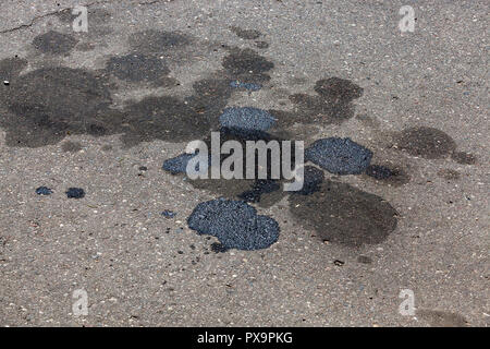 Grandi macchie di olio, olio combustibile e altre emissioni dalle vetture su strada asfaltata, primo piano Foto Stock