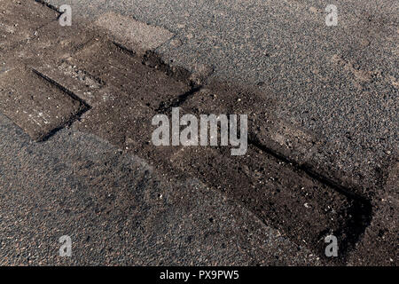 Sawed quadrato e rettangolare aperture sull'asfalto durante le riparazioni, lavori di ripristino della vecchia carreggiata, un close-up Foto Stock