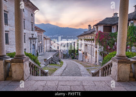 Bellissima scenic alley con gli storici e tradizionali case e strada di ciottoli al tramonto. Il pittoresco villaggio italiano, Orta San Giulio, Italia Foto Stock