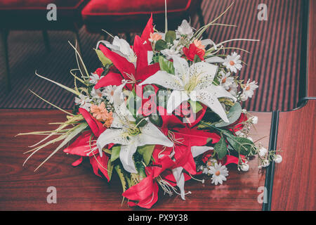 Bouquet di nozze del rosso e del bianco fiori artificiali sul tavolo in ufficio del registro di sistema. Close up. Foto Stock